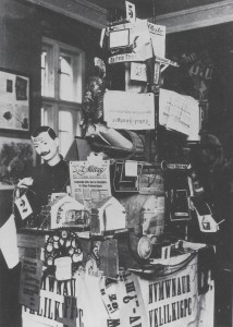 Johannes Baader, Plasto-Dio-Dada-Drama, 1920, Assemblage mit verschiedenen Materialien, darunter Zeitungen, Ofenrohr, Schaufensterpuppe, Zahnrad, Plakate, wohl über 2 m Höhe, nicht erhalten.